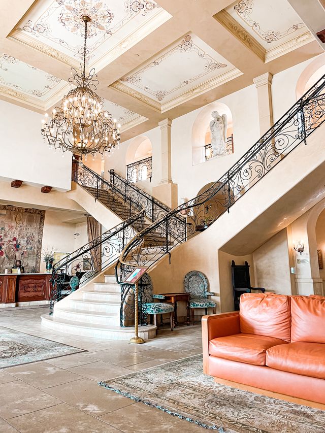 Sweeping staircase with wrought iron railing and a chandelier in a heritage hotel lobby